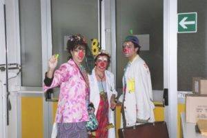 Three clowns wear makeup in a building