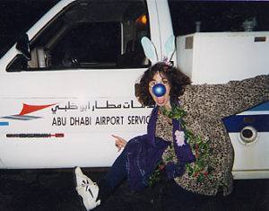 Holly poses in her clown makeup in front of a vehicle at the Abu Dhabi airport