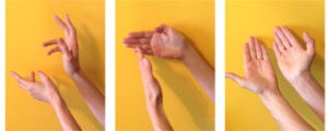 Hands making shapes against a yellow wall