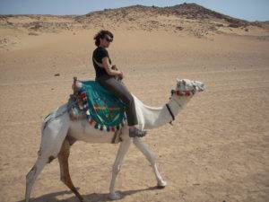 Holly riding a camel in the desert