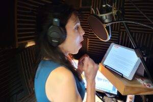Holly Adams warms up in her booth before starting her recording for the day