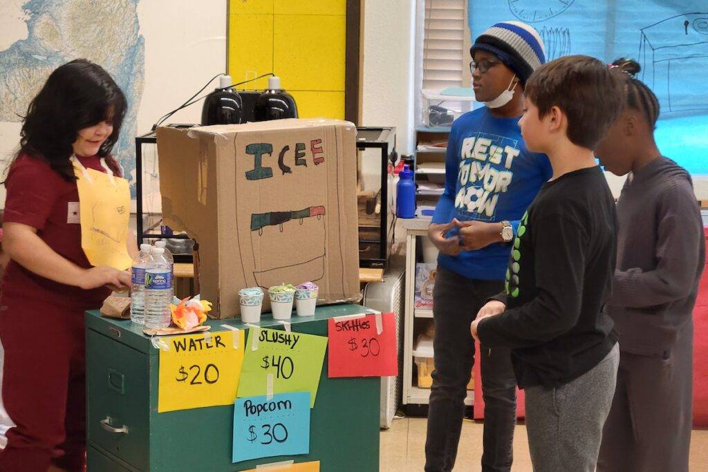 Students rehearse a play about movie theaters with concession props