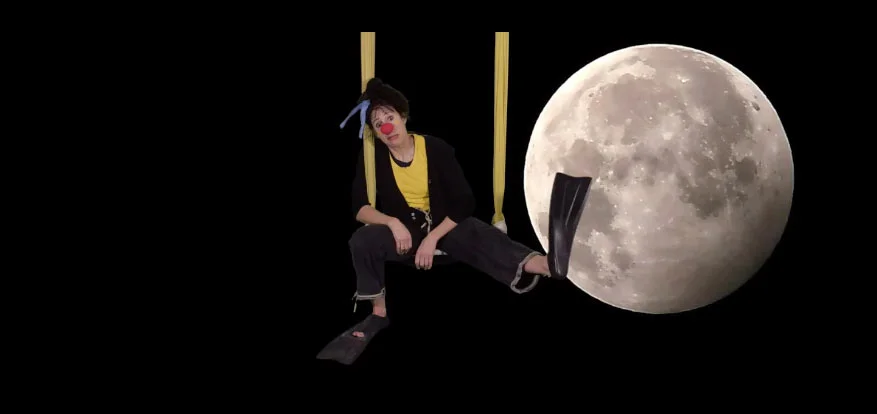 Holly in a clown routine on a trapeze in front of the moon